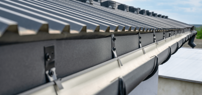 Gutter system installed along a metal roof