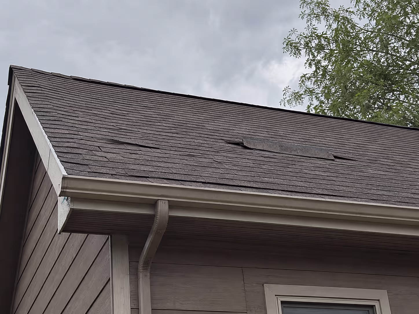 Wind-damaged roof shingles on an Aurora, Colorado home